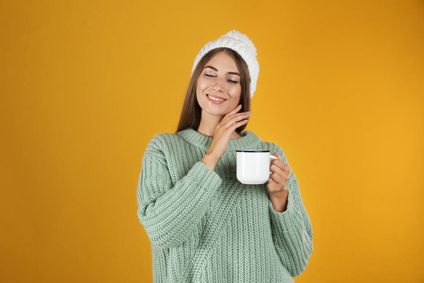 Happy beautiful woman with mug of mulled wine on yellow background - Foto, Imagen