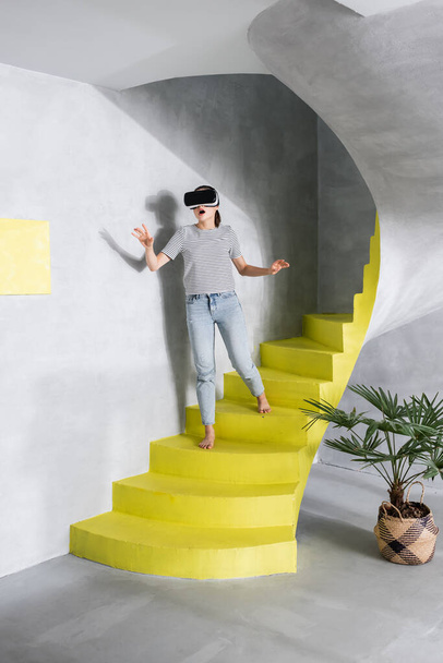 Aufgeregte Frau benutzt Virtual-Reality-Headset im Treppenhaus  - Foto, Bild