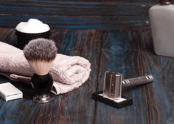 Navajas de afeitar, cepillo, bálsamo y espuma sobre un fondo de madera. - Foto, imagen