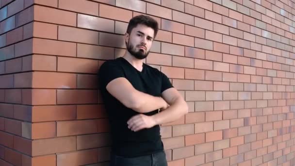 Fier jeune homme appuyé contre un mur de briques - Séquence, vidéo