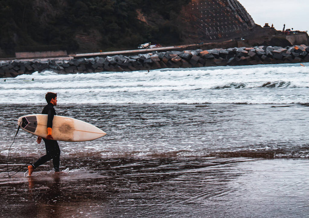 Surfer entering the water with the board under his arm. - Foto, immagini