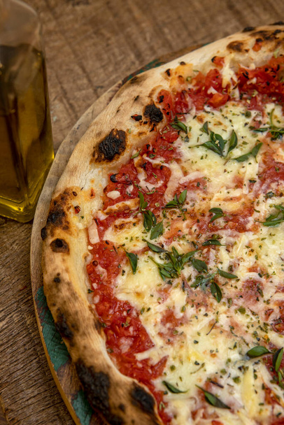 Pizza Margarita ou Margherita aux tomates, fromage mozzarella, sauce tomate et basilic. Pizza napoletana traditionnelle sur table en bois - Photo, image