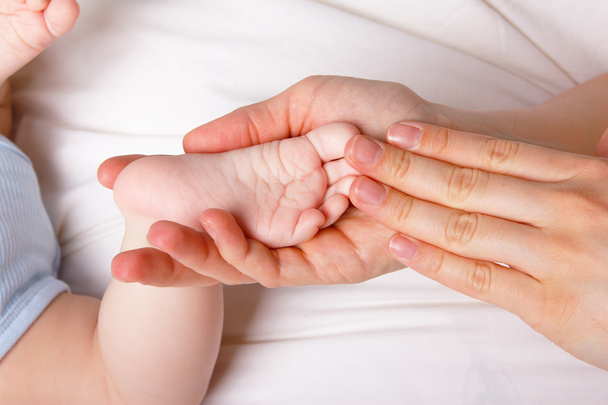 Нога дитини в руці його мами
 - Фото, зображення