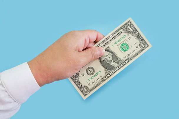 рука ділової жінки тримає 1 долар законопроект ізольовано на синьому фоні
. - Фото, зображення