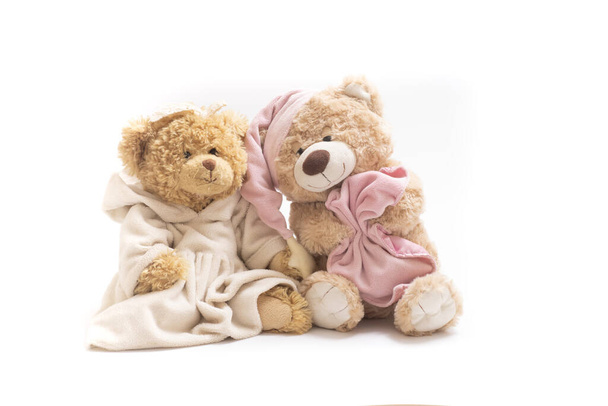 Um par de ursos de brinquedo macio sobre um fundo branco. Urso sonolento em um gorro com uma manta e um urso em um vestido. Conceito de amizade, infância, relacionamentos, sono, adormecer, sonhos. Horizontal. - Foto, Imagem