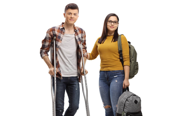 Male student with crutches and a female student helping him isolated on white background - Fotografie, Obrázek