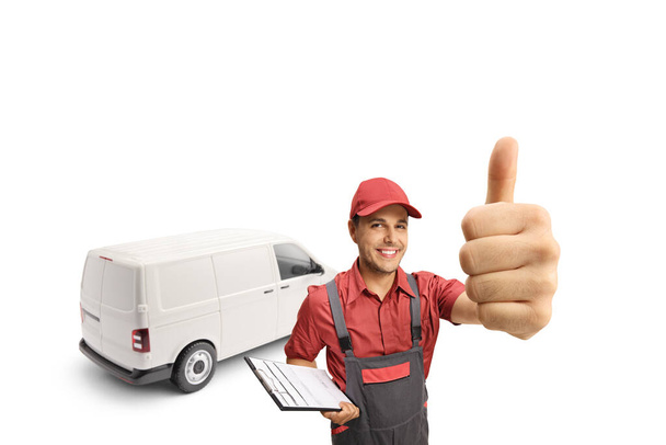 Delivery man with a van holding a clipboard and gesturing a thumb up sign isolated on white background  - Fotó, kép