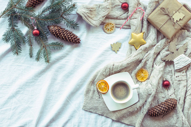 Σύνθεση της Πρωτοχρονιάς με φλιτζάνι καφέ, κουτί δώρου, χριστουγεννιάτικη διακόσμηση, έλατο κλαδί, αποξηραμένα πορτοκάλια και πλεκτό πουλόβερ - Φωτογραφία, εικόνα