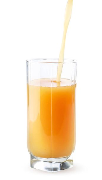 Il succo di frutta viene versato in una tazza di vetro primo piano su uno sfondo bianco. Isolato - Foto, immagini