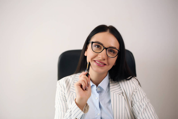 Portrait of smiling pretty young business woman in glasses sitting on workplace - Фото, зображення