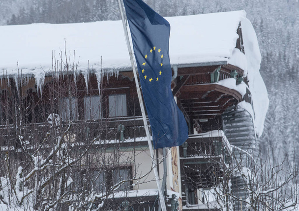 Σημαία της Ευρωπαϊκής Ένωσης το χειμώνα, γαλάζια σημαία με κίτρινα αστέρια που αντιπροσωπεύουν την ΕΕ - Φωτογραφία, εικόνα