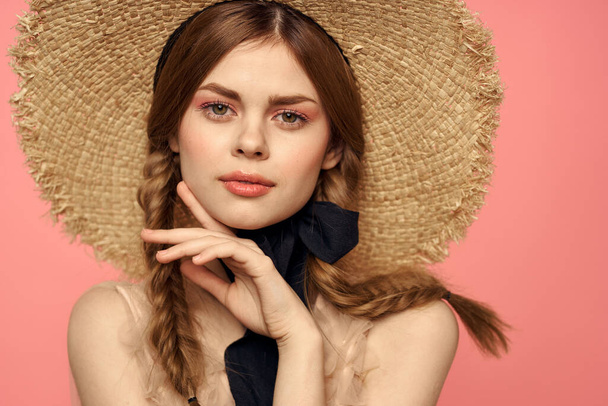 Portrait d'une fille dans un chapeau de paille sur un fond rose émotions gros plan beau visage modèle pigtails - Photo, image