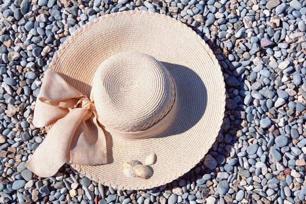 Καπέλο ήλιου στην παραλία με βότσαλα. Καλοκαίρι και διακοπές έννοιες  - Φωτογραφία, εικόνα