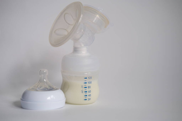 The electric breast pump is on the table in the kitchen. Give expressed breast milk. Breast care for a young mother - Foto, imagen