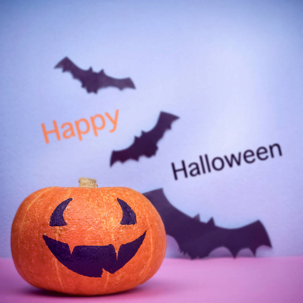  Καλή Halloween δημιουργική κολοκύθα με αστείο χαμόγελο και νυχτερίδες χαρτί στο φόντο Pink Square. Υψηλής ποιότητας φωτογραφία - Φωτογραφία, εικόνα
