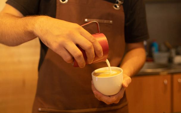 Hands pouring milk making latte art in a coffee. - Fotoğraf, Görsel
