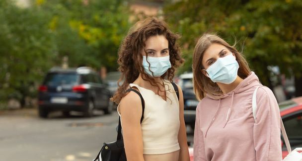 Two young best friends meeting on street wearing a face mask to protection by Coronavirus, Covid-19 and stay security distant. - Photo, Image