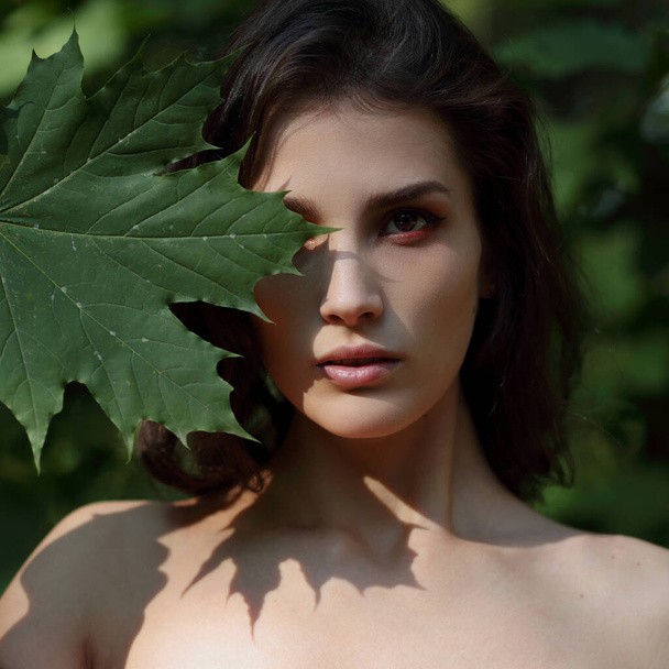 Portrait of a beautiful girl with a green maple leaf - Фото, зображення
