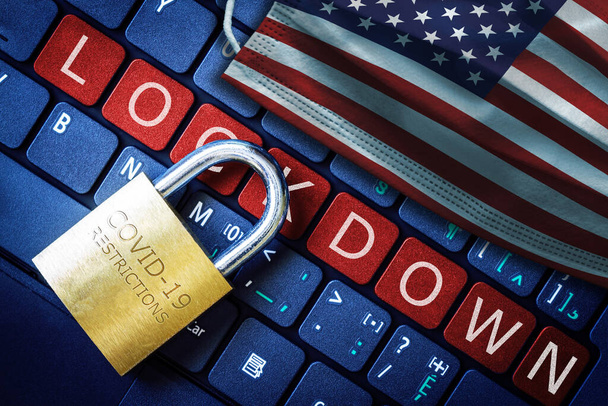 米国COVID-19コロナウイルスロックダウン制限の概念は、ノートパソコンの赤いアラートキーボードボタンとアメリカ国旗付きフェイスマスク上の南京錠で示されています. - 写真・画像