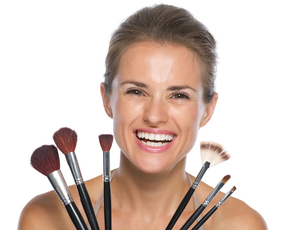 Smiling young woman holding makeup brushes - Fotoğraf, Görsel