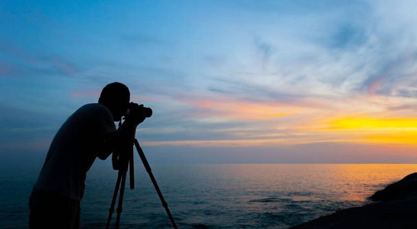 Fotografia professionale uomo scattare una foto tramonto o alba drammatico cielo sul mare tropicale in Phuket Thailandia - Foto, immagini