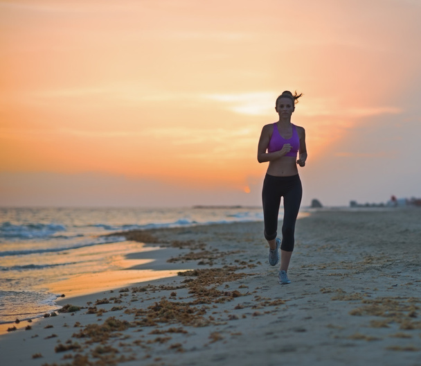 Fitness young woman running on beach in the evening - Фото, зображення