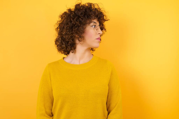 Curly Hair, кавказька жінка в жовтій студії, дивлячись на сторону, копіюйте простір  - Фото, зображення