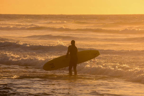 Sakin bir okyanusta gün batımında tek bir sörfçü - Fotoğraf, Görsel