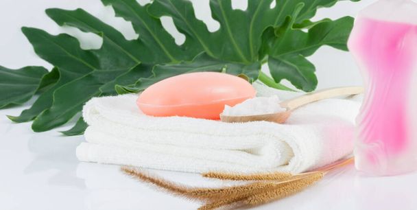 Savon de bar sur serviettes blanches propres, feuilles vertes et frotter le sel sur des scènes blanches pour l'hygiène. - Photo, image