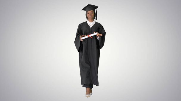 Young african graduate student walking and laughing on gradient - Foto, imagen