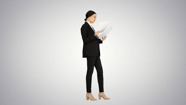 Serious Brunette Businesswoman reading documents on gradient bac - Photo, Image