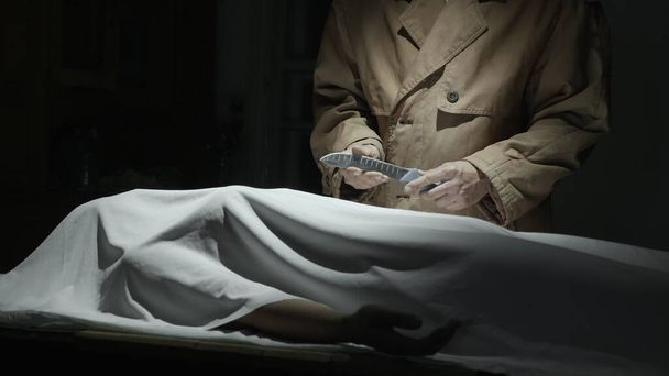 Маньяк в плаще стоит над жертвой с ножом - Фото, изображение