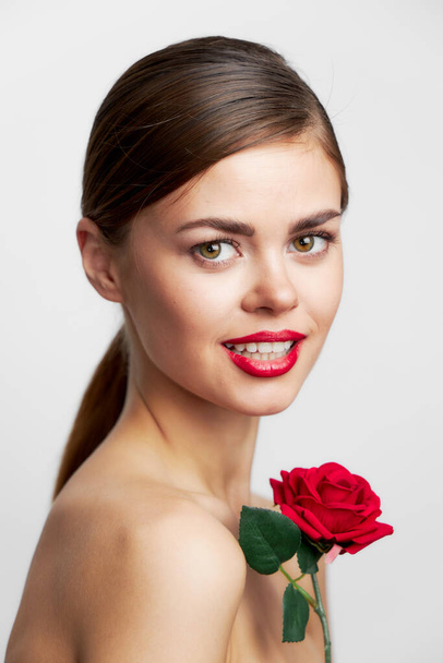 Μελαχρινή με γυμνούς ώμους χαμόγελο κόκκινο τριαντάφυλλο γοητευτικό βλέμμα - Φωτογραφία, εικόνα
