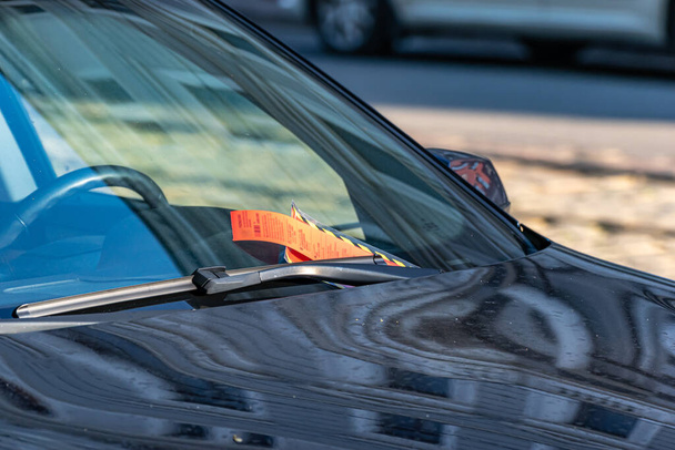 駐車中の車のフロントガラスに赤いペナルティ領収書。フロントガラスには駐車券が快適に設置されています。. - 写真・画像