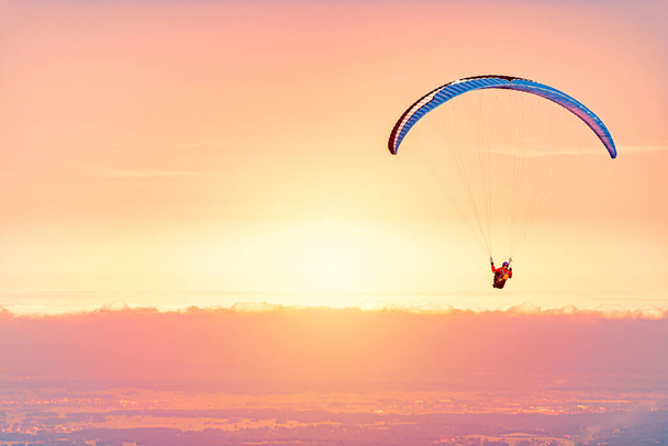 Paraglider at sunset in Germany, Bavaria, Europe. Orange sky with clouds in background. - Photo, Image