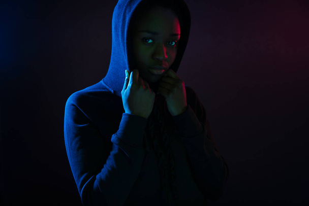 Σκούρο πολύχρωμο πορτραίτο στούντιο μιας γαμάτης μαύρης γυναίκας με κουκούλα - Φωτογραφία, εικόνα