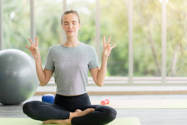 Молодая привлекательная улыбающаяся женщина практикует йогу тренировки, носить спортивную одежду, спокойствие и расслабиться, женское счастье. - Фото, изображение