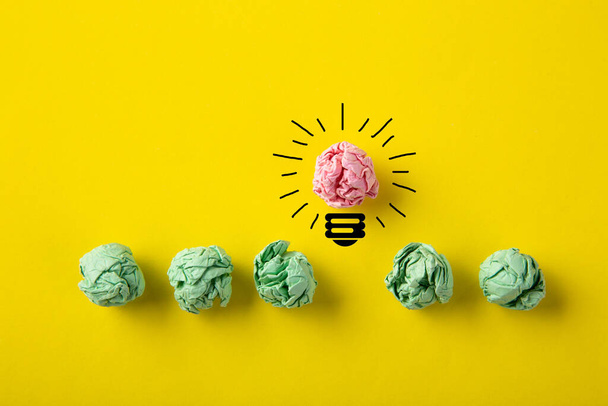 Inspiration concept crumpled paper light bulb metaphor for good idea on yellow background - 写真・画像