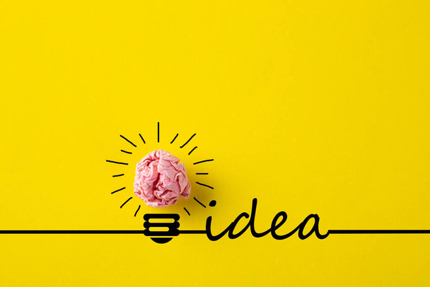 Yaratıcı fikir, ilham, yeni fikir ve yenilik kavramı. Sarı arka planda buruşuk kağıt ampulle.. - Fotoğraf, Görsel