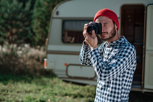 Homme avec une caméra prenant une photo dans la nature près de la remorque à la maison. - Photo, image