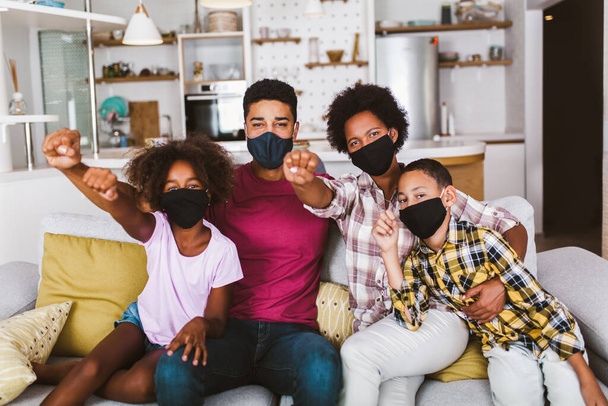 Афроамериканських батьків і маленьких маленьких дітей, які носять захисні маски вдома. Зупиніть вірус і епідемічні хвороби.. - Фото, зображення