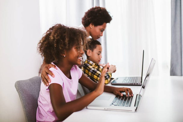 Étudiants afro-américains du primaire utilisant un ordinateur et suivant des cours en ligne en raison de la pandémie de coronavirus. - Photo, image