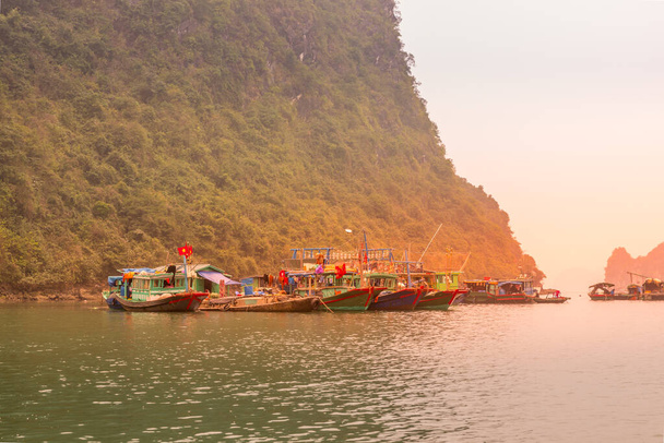 Vista deslumbrante do pôr do sol da vila de pescadores flutuantes em Halong Bay (Descendente Dragon Bay) no Golfo de Tonkin do Mar da China Meridional, Vietnã. Paisagem formada por torres-ilhas cársticas. - Foto, Imagem
