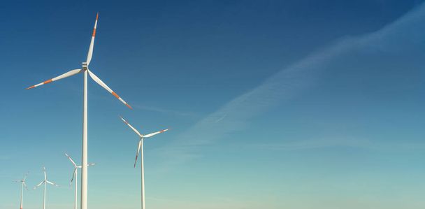 Banner pari iso tuuliturbiinit tuottaa sähköä, vihreä ympäristöystävällistä energiaa sinisellä taivaalla auringonlaskun lämpimät värit kopioi tilaa tekstiä - Valokuva, kuva