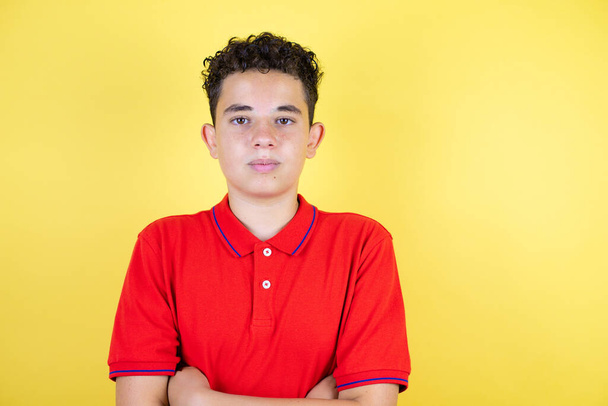 Beautiful teenager boy over isolated yellow background serious looking at the camera - Φωτογραφία, εικόνα