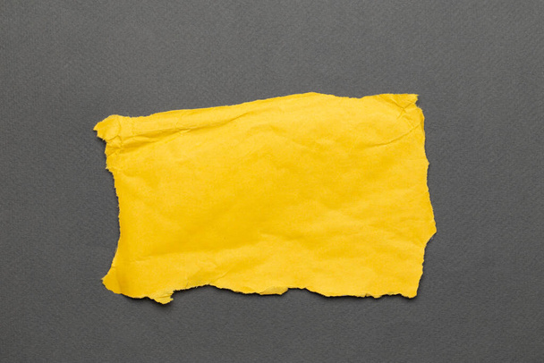 Roztrhaný skutečný papír žluté barvy zbytky na šedém pozadí. Horní pohled - Fotografie, Obrázek