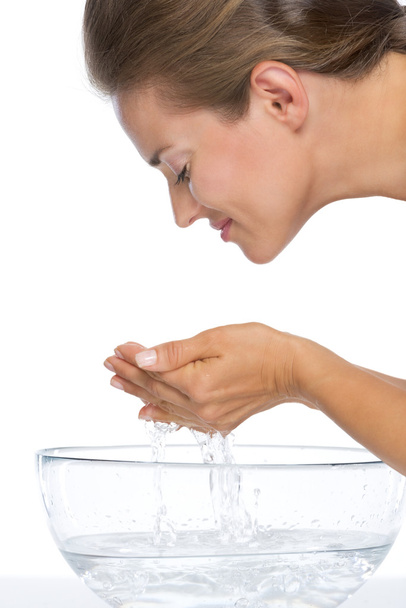 Young woman washing face in glass bowl with water - Foto, Imagem