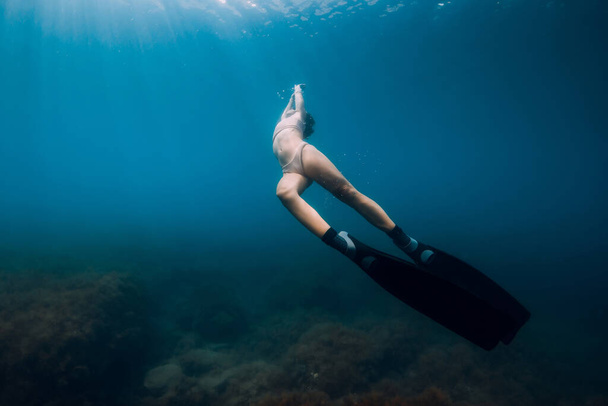 Свободный ныряльщик скользит с плавниками под водой. Женщина занимается фридайвингом в море - Фото, изображение
