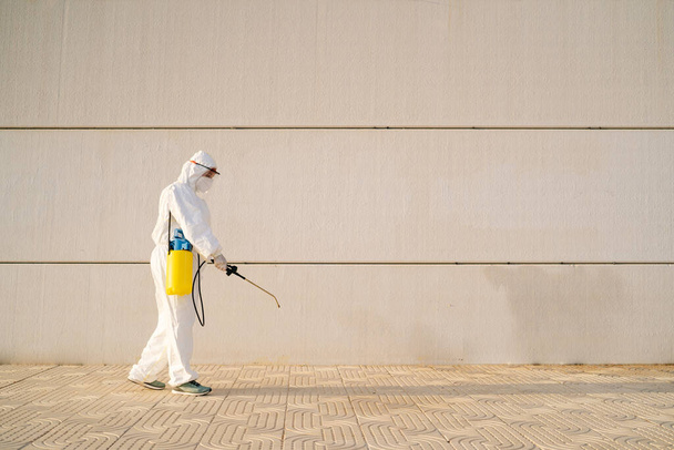 Man in virus protective suit and mask disinfecting buildings with the sprayer. - Fotoğraf, Görsel
