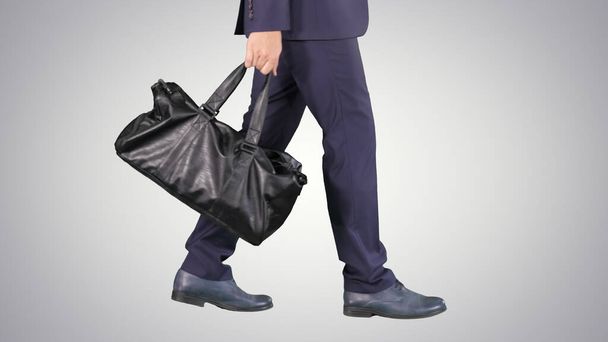 Busy man walking with leather bag on gradient background. - 写真・画像